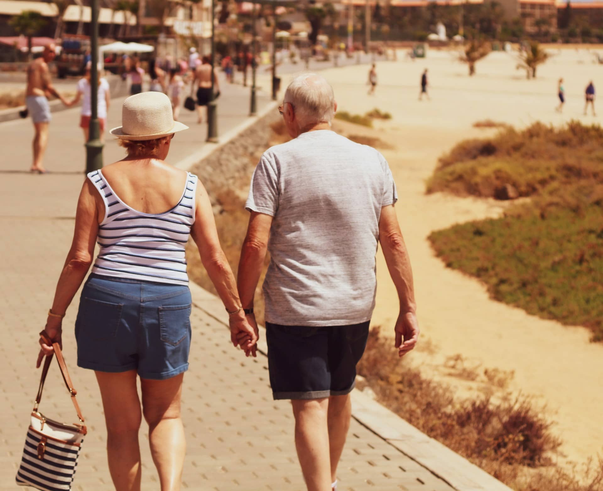 A man and woman walking hand in hand along a serene road, symbolizing enduring partnership and a metaphor for the average American life expectancy.