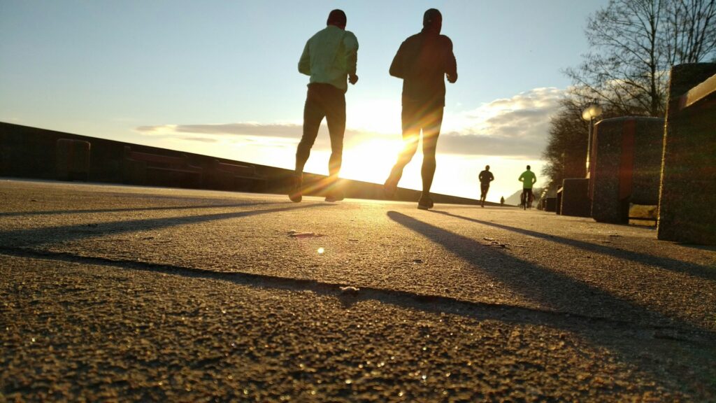 Two men running energetically in a park, showcasing the essence of vitality and wellness through their commitment to fitness and health.