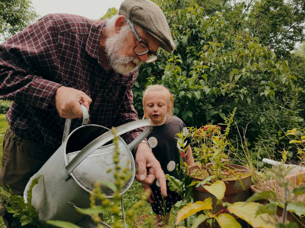 Vital elderly man working in the garden with a child